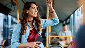 Mulher branca usa fones de ouvido para escutar podcast no ônibus